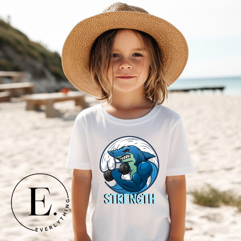 Dive into strength and style with our kids' shirt. Featuring a shark lifting weights with the empowering word 'strength' underneath on a white shirt. 