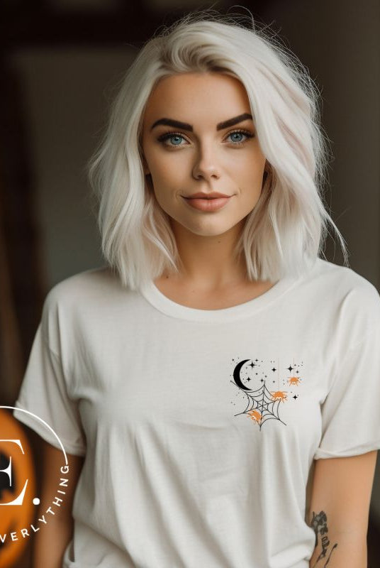 Embrace the enchanting night sky with our captivating t-shirt. Featuring a crescent moon, stars, and a spiderweb with three adorable spiders hanging down on the front pocket on a white shirt. 