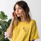 Embrace the enchanting night sky with our captivating t-shirt. Featuring a crescent moon, stars, and a spiderweb with three adorable spiders hanging down on the front pocket on a yellow shirt. 