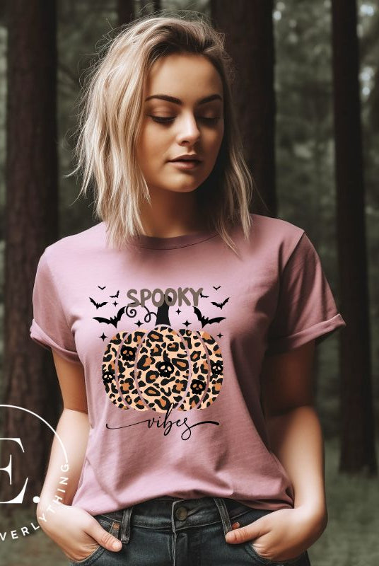 Get into Halloween spirit with our spooky vibes shirt featuring a unique cheetah print pumpkin adorned with skulls. As bats soar across the starry sky, embrace the eerie charm of this one-of-a-kind design on a pink shirt. 