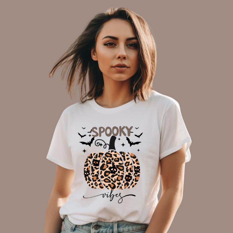 White t-shirt featuring a leopard-print pumpkin and "Spooky Vibes" text surrounded by bats, perfect for Halloween and fall season style.