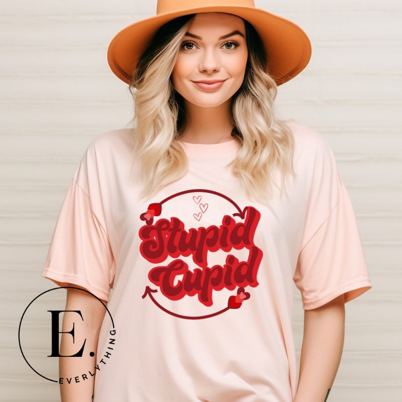 Express your Valentine's Day attitude with our bold and cheeky shirt proclaiming "Stupid Cupid" on a peach shirt. 