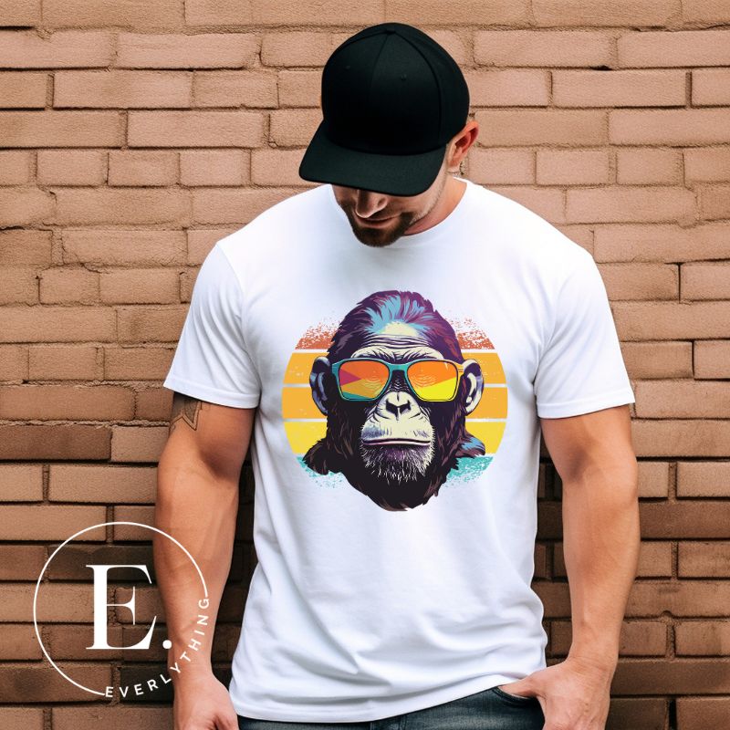 A gorilla wearing sunglasses Infront of a retro sunset on a white colored shirt.