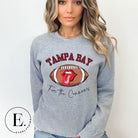 Get ready to showcase your support for the Tampa Bay Buccaneers with this eye-catching sweatshirt. Featuring a football and playful lips and tongue design, it proudly displays the team's rallying cry "Fire the Cannons" and the distinctive Tampa Bay wordmark on a grey sweatshirt. 