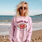 Get ready to showcase your support for the Tampa Bay Buccaneers with this eye-catching sweatshirt. Featuring a football and playful lips and tongue design, it proudly displays the team's rallying cry "Fire the Cannons" and the distinctive Tampa Bay wordmark on a light pink sweatshirt. 