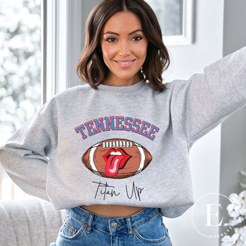 Elevate your game-day look with this Tennessee Titans sweatshirt, featuring a football and unique lips and tongue design. Complete with the team's rallying cry "Titan Up" and the iconic Tennessee wordmark, on a grey sweatshirt. 
