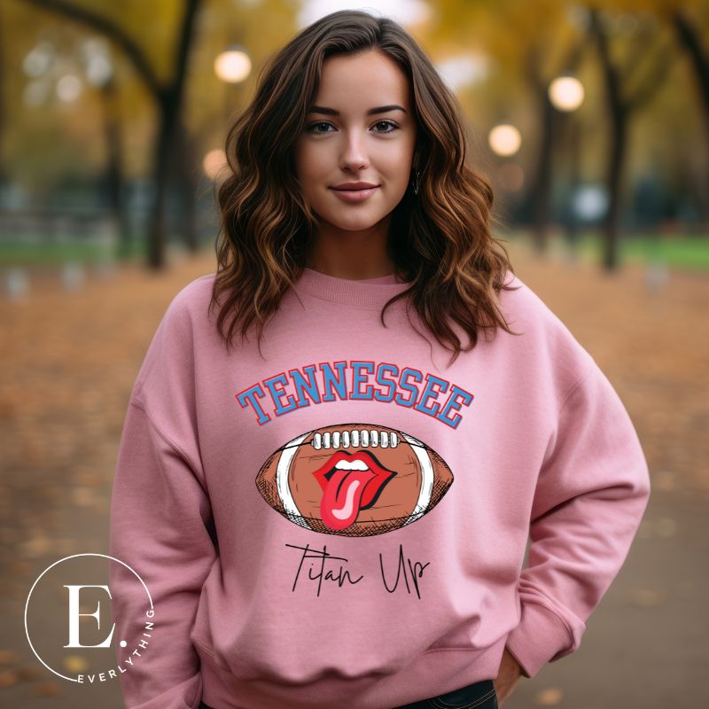 Elevate your game-day look with this Tennessee Titans sweatshirt, featuring a football and unique lips and tongue design. Complete with the team's rallying cry "Titan Up" and the iconic Tennessee wordmark, on alight pink sweatshirt. 