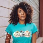 Express gratitude in style with our charming t-shirt. This design radiates autumn appreciation, featuring three pastel pumpkins and the word 'thankful' gracefully woven through the middle on a blue shirt. 