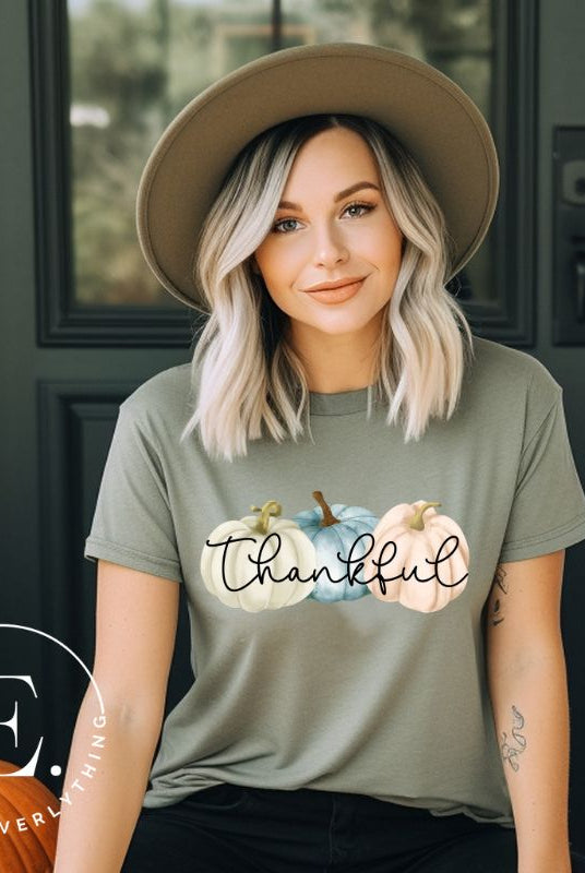 Express gratitude in style with our charming t-shirt. This design radiates autumn appreciation, featuring three pastel pumpkins and the word 'thankful' gracefully woven through the middle on a green shirt. 