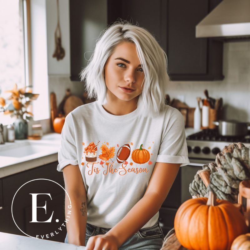 Get ready to welcome the fall season with our exclusive 'Tis The Season' football shirt! This vibrant design features fall coffee, leaves, football, and pumpkins, perfectly capturing the essence of autumn on a black shirt. 