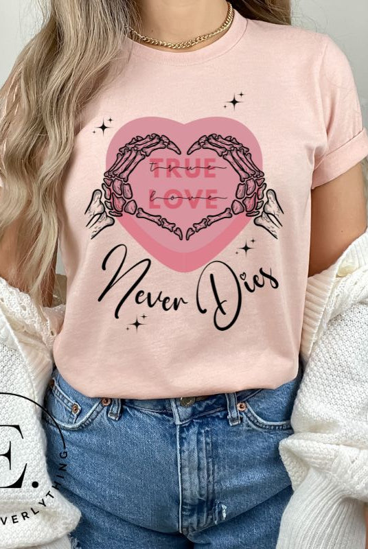 Embrace the unconventional with our Valentine's Day shirt featuring the bold statement "True Love, Never Dies" adorned with a heart and skeleton hands forming a heart shape on a peach shirt. 
