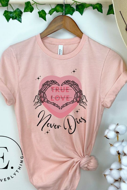 Embrace the unconventional with our Valentine's Day shirt featuring the bold statement "True Love, Never Dies" adorned with a heart and skeleton hands forming a heart shape on a pink shirt. 