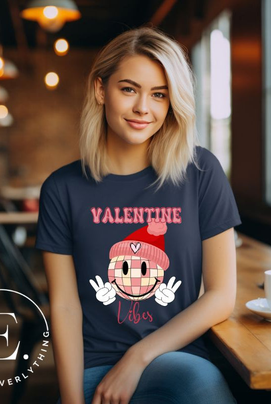 Get into the Valentine's Day spirit with our fun and funky shirt donning the words "Valentine Vibes" alongside a disco ball smiley face flashing peace fingers on a navy shirt. 