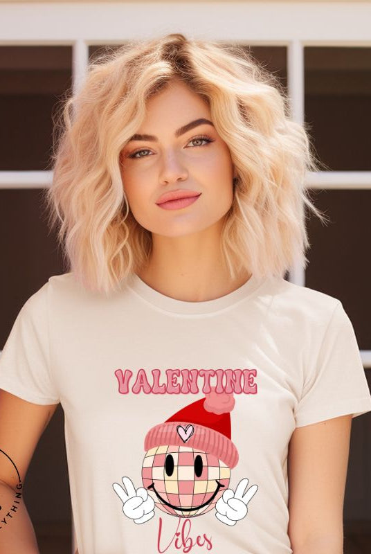 Get into the Valentine's Day spirit with our fun and funky shirt donning the words "Valentine Vibes" alongside a disco ball smiley face flashing peace fingers on a soft cream shirt. 