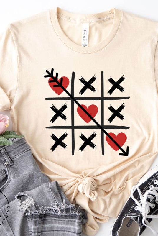 Add a playful twist to Valentine's Day with our Tic-Tac-Toe shirt featuring exes and three hearts. The winning move, an arrow through the three hearts, adds a cheeky touch to this fun and stylish soft cream shirt. 