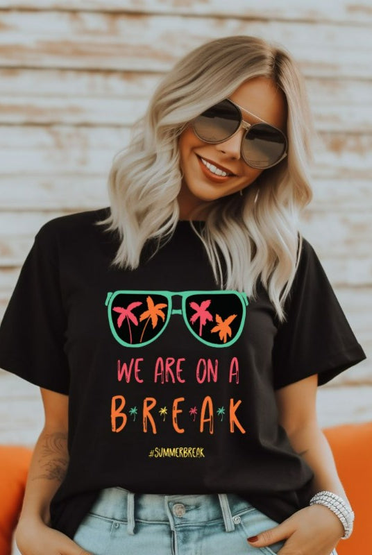 Graphic tee with the saying 'We Are On Break' and sunglasses reflecting palm trees - a fun option for teacher shirts and teacher gifts. Black graphic tees.