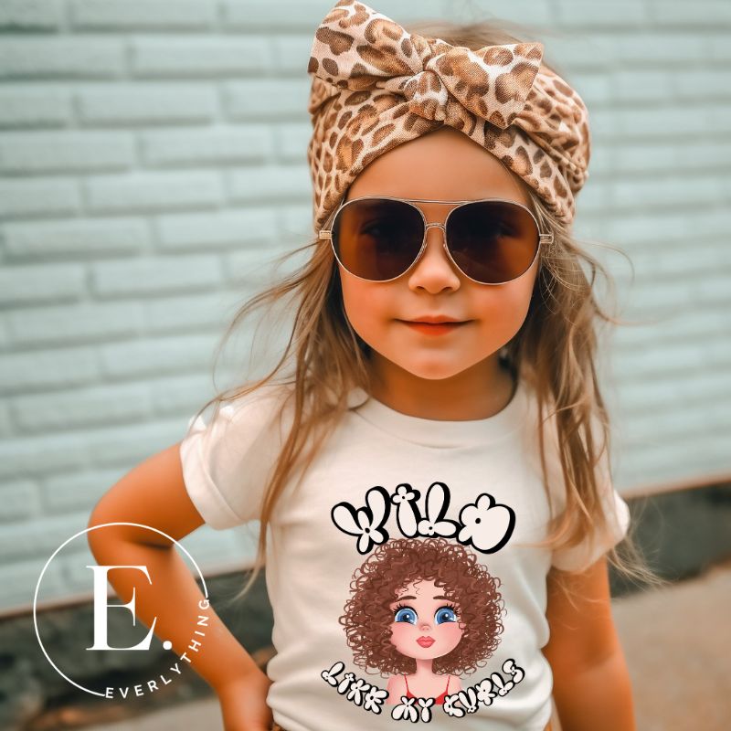 Embrace the beauty of wild curls with our kids' shirt. Featuring an adorable girl with curly hair and the empowering saying ' Wild Like My Curls,' on a soft cream shirt. 