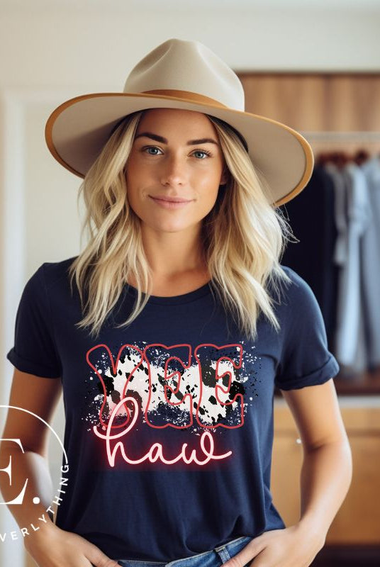 Saddle up in style with our country western shirt featuring the spirited exclamation "Yeehaw" set against a sleek cowhide print background, accented with neon pink lettering on a navy shirt. 