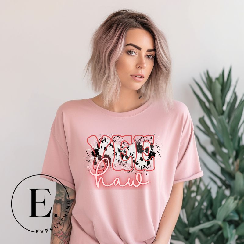 Saddle up in style with our country western shirt featuring the spirited exclamation "Yeehaw" set against a sleek cowhide print background, accented with neon pink lettering on a pink shirt. 