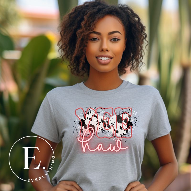 Saddle up in style with our country western shirt featuring the spirited exclamation "Yeehaw" set against a sleek cowhide print background, accented with neon pink lettering on a grey shirt. 