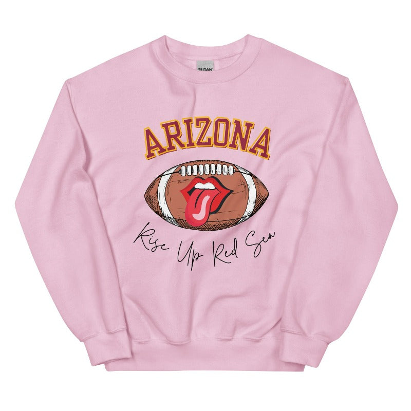 Support the Arizona Cardinals in style with our exclusive sweatshirt featuring the team's name and rallying slogan, "Rise Up Red Sea." On a light pink sweatshirt. 