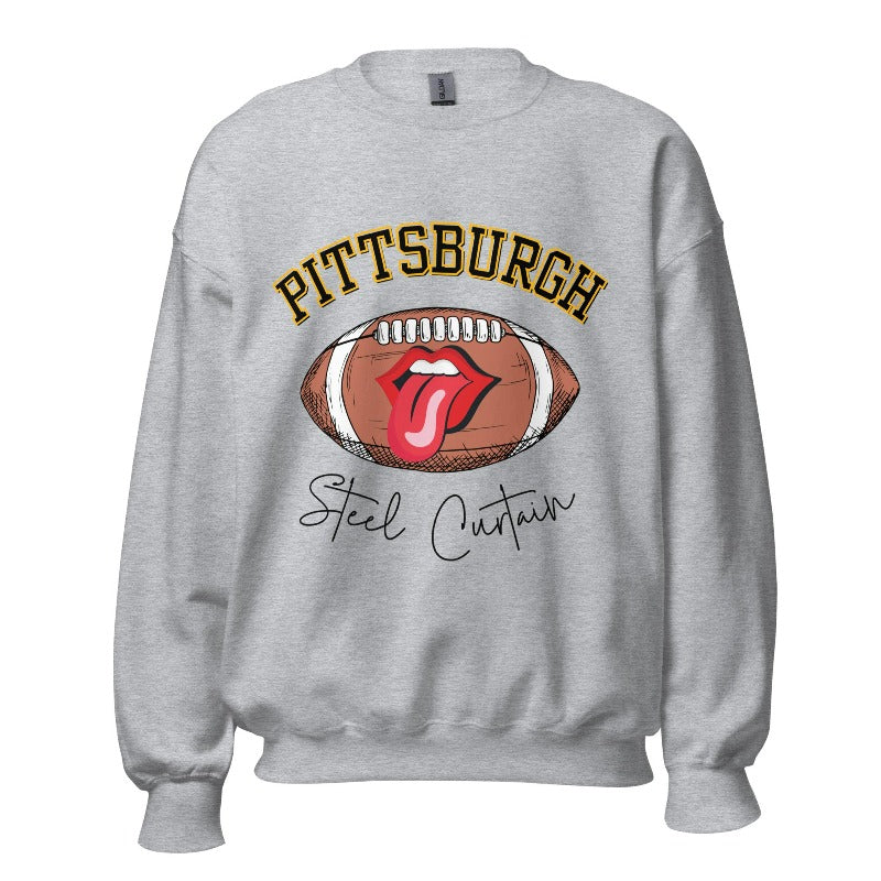 Geer up for game day with this Pittsburgh Steelers sweatshirt, featuring a football and playful lips and tongue design. Emblazoned with the team's iconic slogan "Steel Curtain" and the distinctive Pittsburgh wordmark, on a grey sweatshirt. 