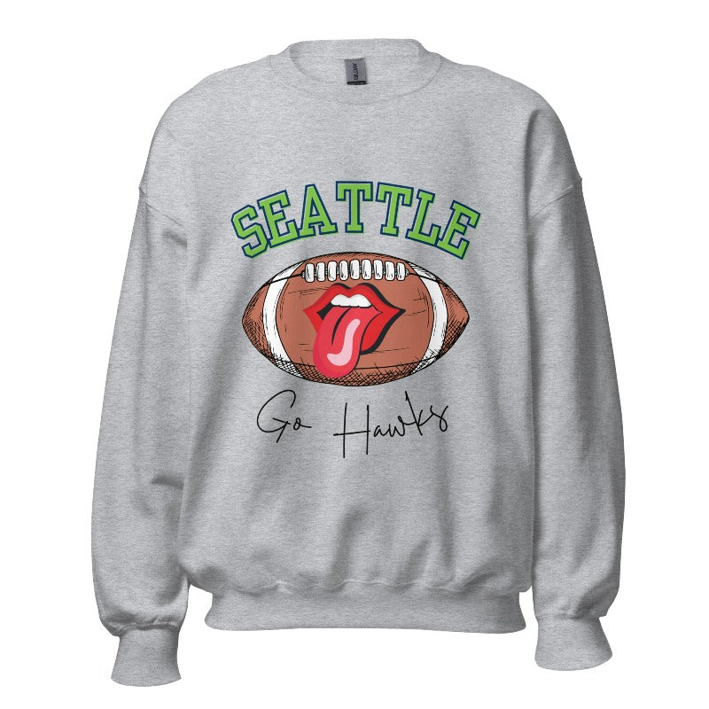 Support the Seattle Seahawks in style with this unique sweatshirt featuring a football and playful lips and tongue design. Featuring the team's slogan "Go Hawks" and the iconic Seattle wordmark, on a sports grey sweatshirt. 