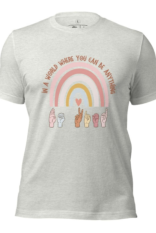 American sign language shirt with a rainbow and the phrase "In a world where you can be anything" and hands signing 'Be Kind' at the bottom on the rainbow on a ash colored shirt.