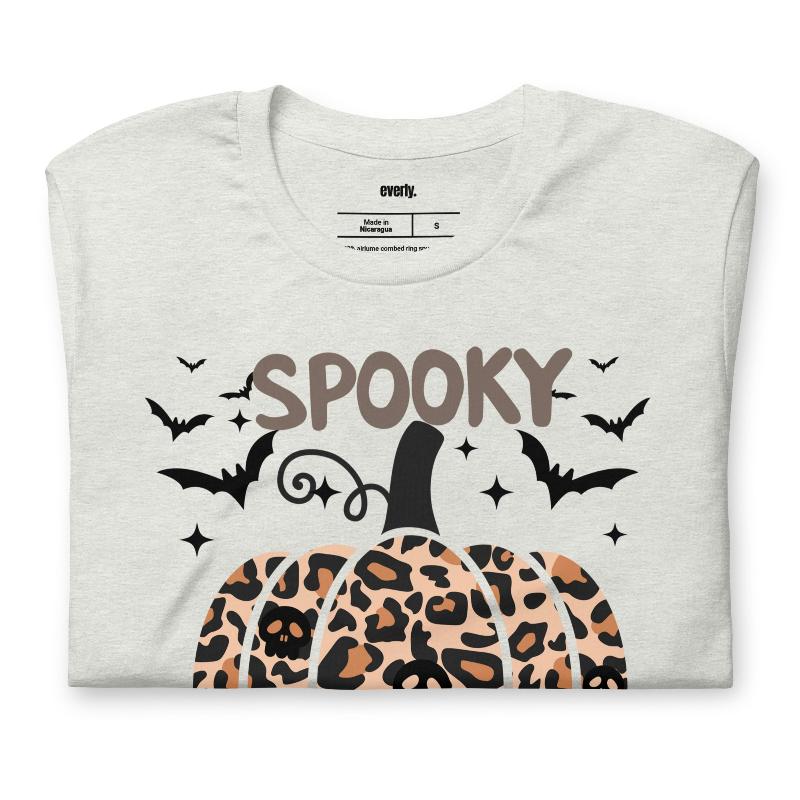 Ash t-shirt featuring a leopard-print pumpkin and "Spooky Vibes" text surrounded by bats, perfect for Halloween and fall season style.