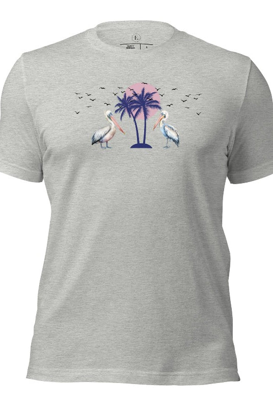 Elevate your beach style with our Beach shirt featuring two majestic pelicans facing each other. Set against a backdrop of a breathtaking sunset and a swaying palm tree on an athletic heather grey shirt. 