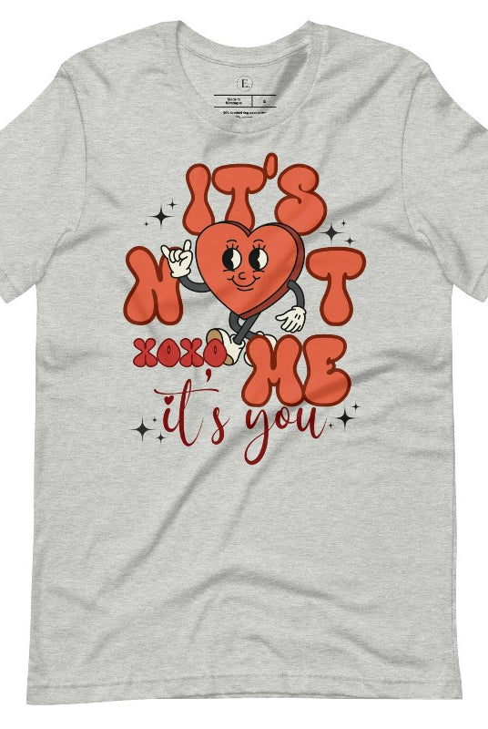 Celebrate Valentine's with our playful shirt! Featuring a bold heart and the message "It's not me, it's you," on an athletic heather grey shirt. 