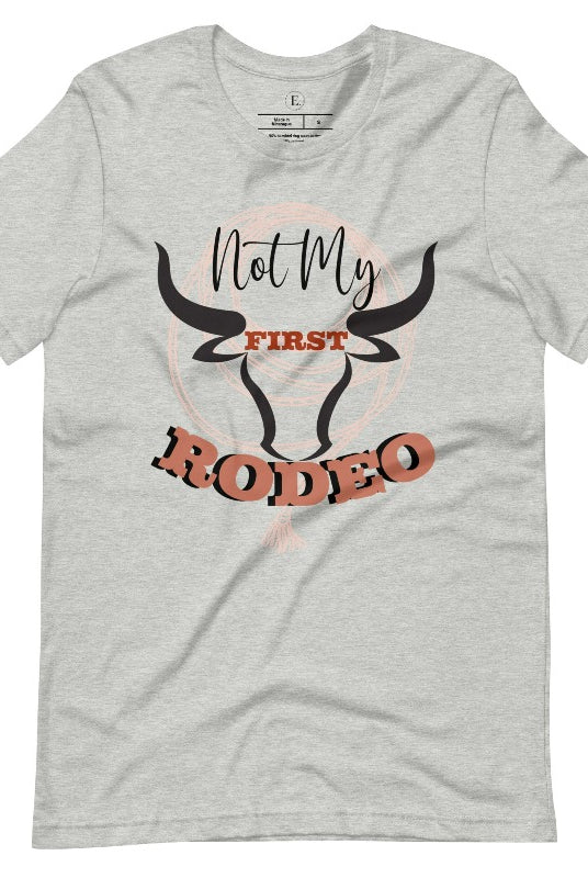 Unleash your cowboy spirit with our country western t-shirt boasting the statement "Not my First Rodeo" alongside bold bull horns and a lasso design on an athletic heather grey shirt. 