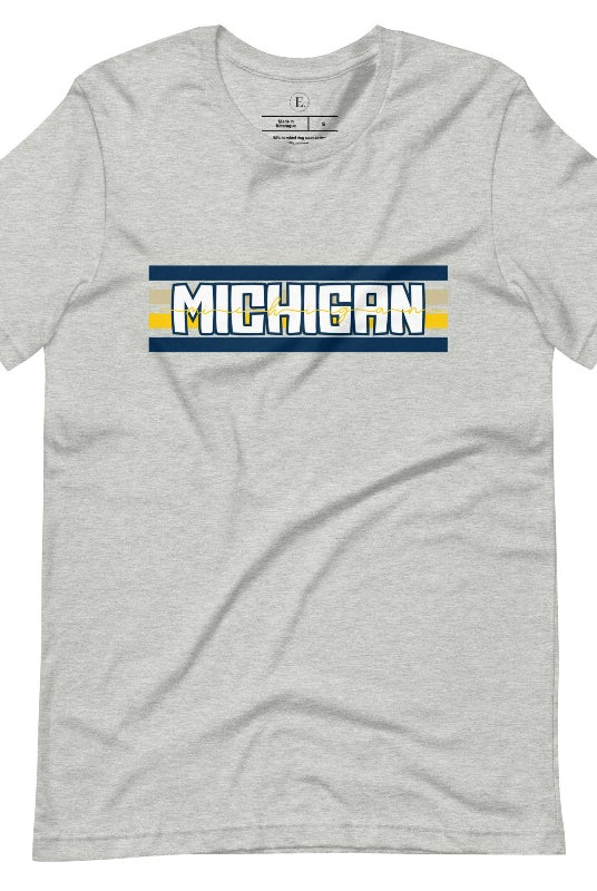 Elevate your collegiate style with our Michigan University graphic tee featuring iconic school colors and bold chest stripes. Emblazoned with "Michigan" in striking lettering, on an athletic heather grey shirt. 