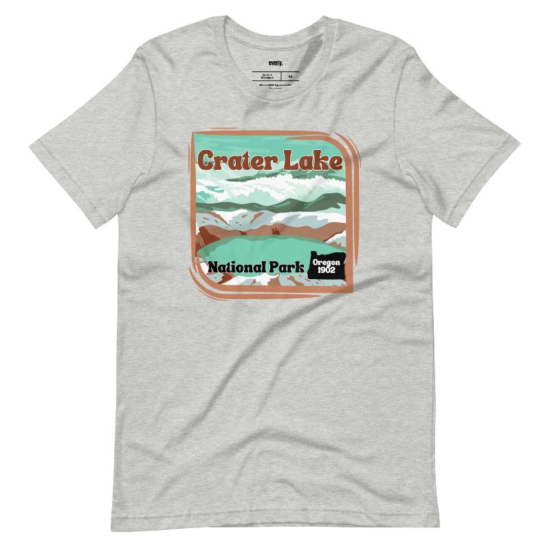 a colorful graphic of Crater Lake National Park, featuring mountains, water, and the text "Crater Lake National Park Oregon 1902 on a grey shirt. 