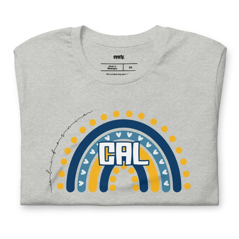 Bella + Canvas 3001 unisex t-shirt featuring a playful blue and gold rainbow design with "CAL" in the center, surrounded by hearts and dots on a grey graphic tee.