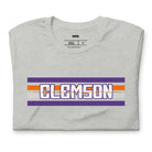 Bella + Canvas 3001 unisex shirt with Clemson University stripe design in purple, orange, and white, with "Clemson" written in bold letters on a athletic heather graphic tee.