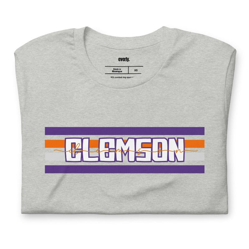 Bella + Canvas 3001 unisex shirt with Clemson University stripe design in purple, orange, and white, with "Clemson" written in bold letters on a athletic heather graphic tee.