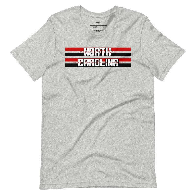 "North Carolina" in bold red and white text on a black and red striped background across the chest on a grey shirt.