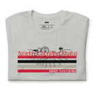 A vibrant NC State design with "North Carolina State" written in red across the top, stripes in red, black, and white, and "Raleigh, North Carolina" at the bottom on a grey graphic tee.