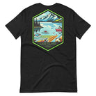 Back view of a black heather Bella + Canvas 3001 unisex shirt featuring a colorful design of Lake Clark National Park with mountains, lake, and wildlife. Inset shows the front view with "Lake Clark National Park | Alaska - 1980" text on a black shirt