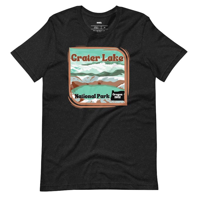 a colorful graphic of Crater Lake National Park, featuring mountains, water, and the text "Crater Lake National Park Oregon 1902 on a black shirt. 