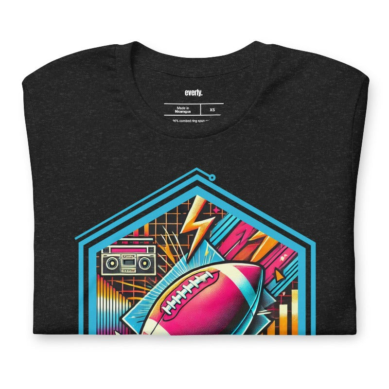 a vibrant neon design of a football with retro elements like boomboxes and geometric patterns, set in a hexagonal frame on a black shirt.