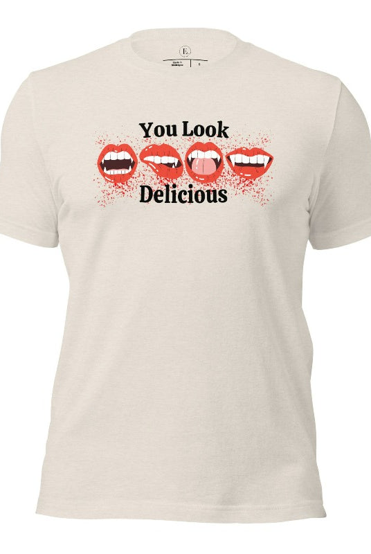 Indulge in wickedly delightful style with our vampire lips shirt. Featuring alluring lips dripping with Halloween allure, this shirt captivates with its seductive charm. The cheeky message, 'You Look Delicious,' on a heather dust colored shirt. 