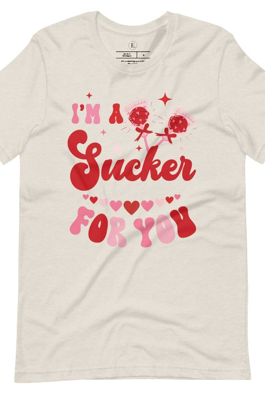 Indulge in the spirit of love with our Valentine's Day shirt! Adorned with charming Valentine lollipops and the playful saying, "I'm a sucker for you," on a heather dust shirt. 