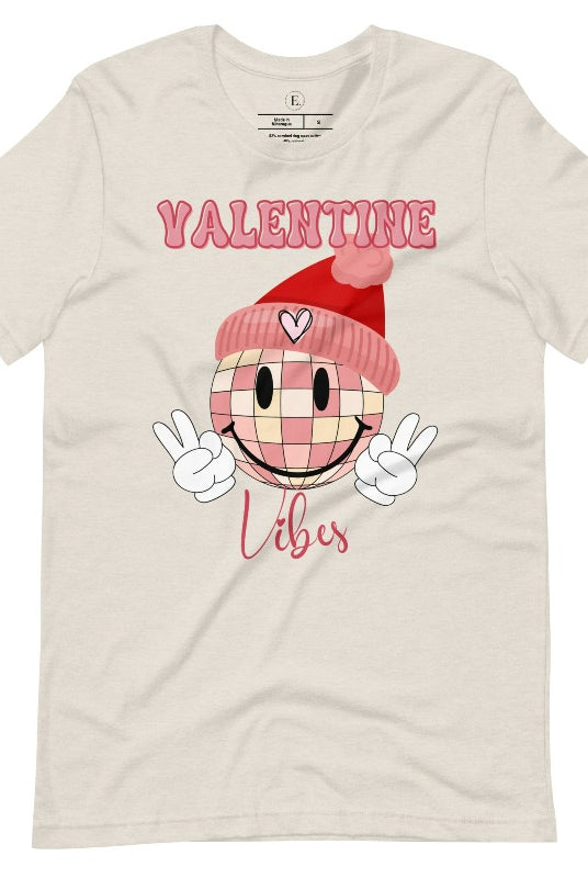 Get into the Valentine's Day spirit with our fun and funky shirt donning the words "Valentine Vibes" alongside a disco ball smiley face flashing peace fingers on a heather dust colored shirt. 