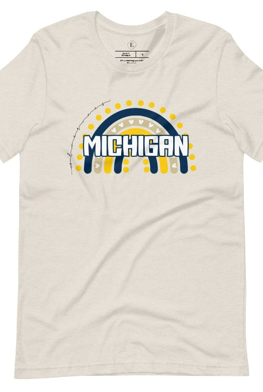 Unleash your vibrant spirit with our Michigan graphic tee. Adorned with a rainbow in school colors and "Michigan" in playful block bubble lettering, this shirt exudes energy and Wolverine pride on a heather dust colored shirt. 