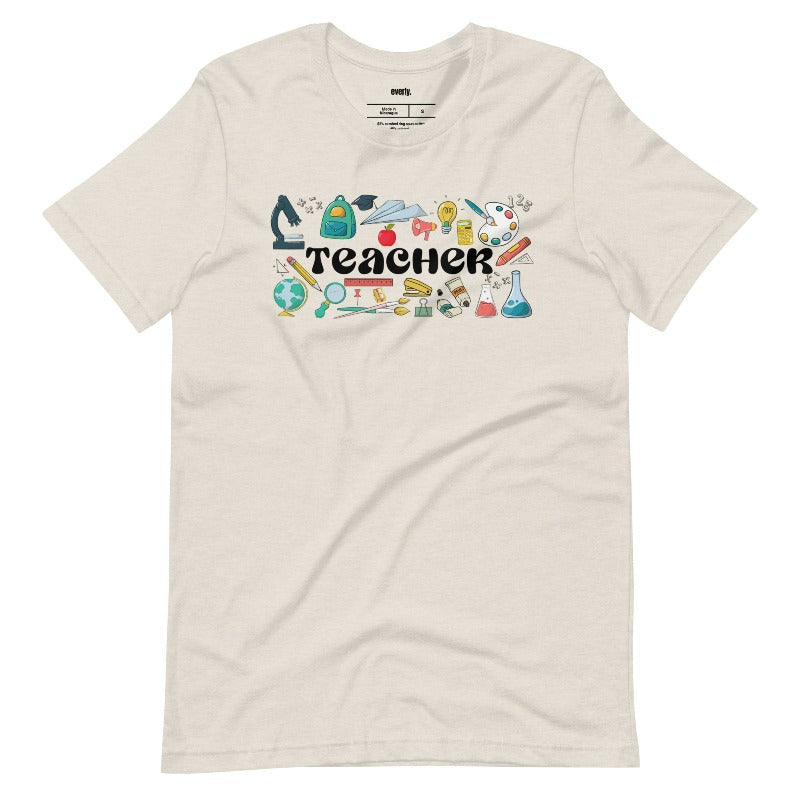 Teacher-themed graphic tee featuring the word 'Teacher' surrounded by all things related to teaching. Perfect for teacher shirts and teacher gifts. Cream graphic tees. 