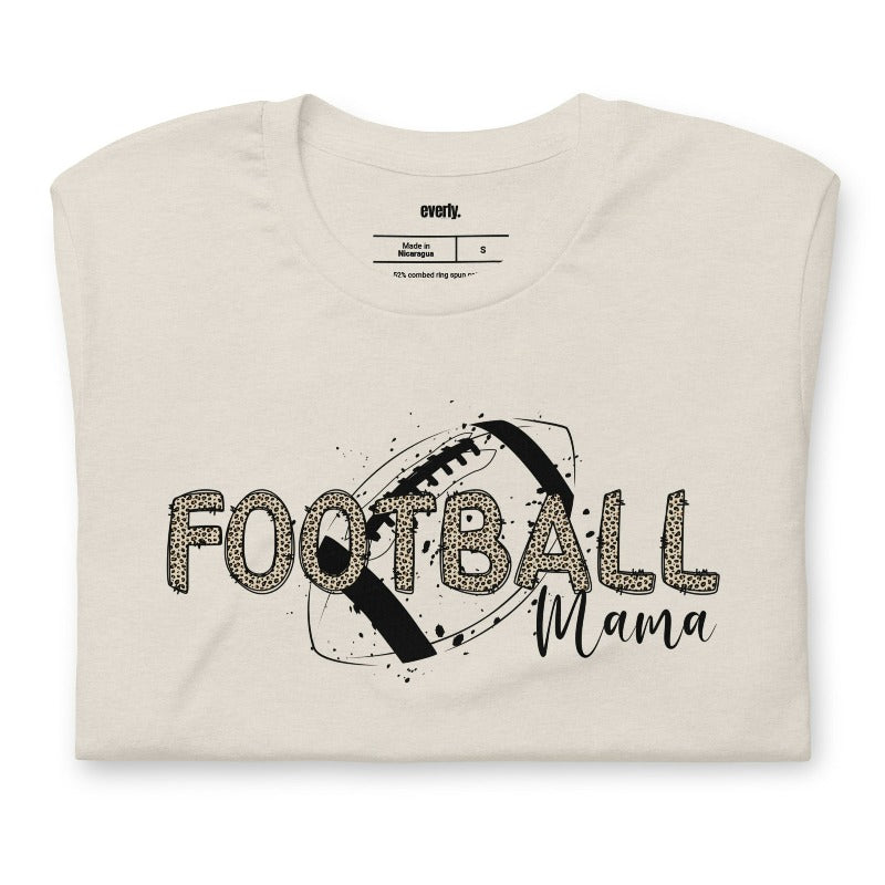 a playful design with a football graphic and the words "Football Mama" in leopard print on a beige shirt.