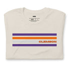 Bella + Canvas 3001 unisex T-shirt featuring a Clemson University design with purple, orange, and grey stripes and the word "Clemson" in bold orange letters on a beige shirt