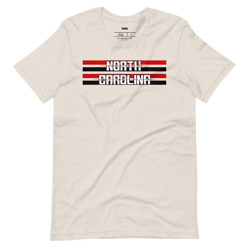 "North Carolina" in bold red and white text on a black and red striped background across the chest on a beige shirt.